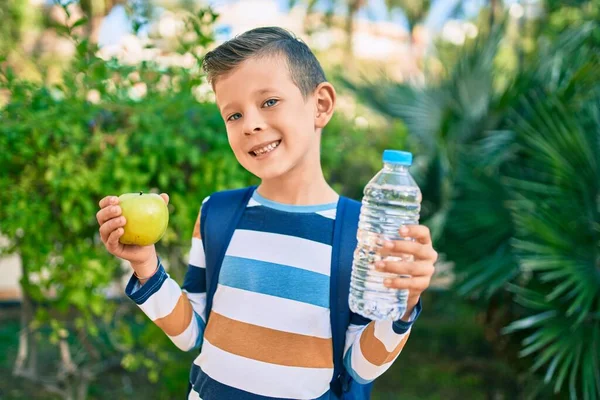 公園で緑のリンゴと水を持って幸せな笑顔の愛らしい白人学生の男の子 — ストック写真