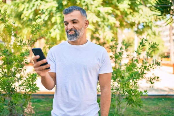Μεσήλικας Γκριζομάλλης Άντρας Χαμογελά Χαρούμενος Χρησιμοποιώντας Smartphone Στο Πάρκο — Φωτογραφία Αρχείου
