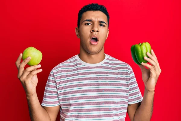 Hombre Árabe Joven Sosteniendo Manzana Verde Pimienta Cara Choque Mirando — Foto de Stock