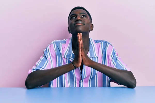 Νεαρός Αφροαμερικάνος Που Φοράει Καθημερινά Ρούχα Κάθεται Στο Τραπέζι Ικετεύοντας — Φωτογραφία Αρχείου