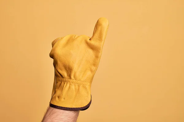 手のCaucasian若いです男とともに庭師手袋上の隔離された黄色の背景ショー小さな指としてピンク約束コミットメント ナンバーワン — ストック写真