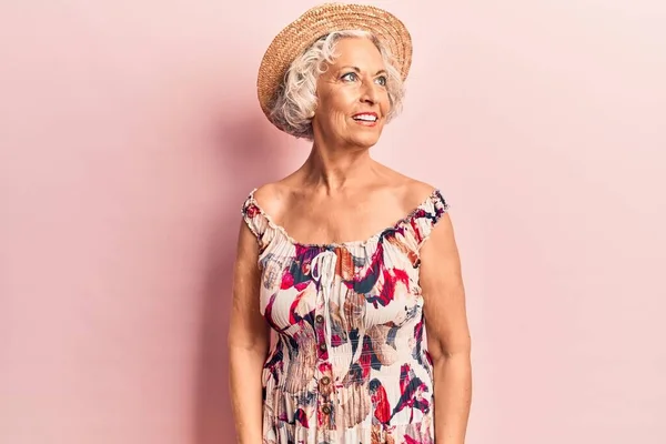 Senior grey-haired woman wearing summer hat looking to side, relax profile pose with natural face and confident smile.