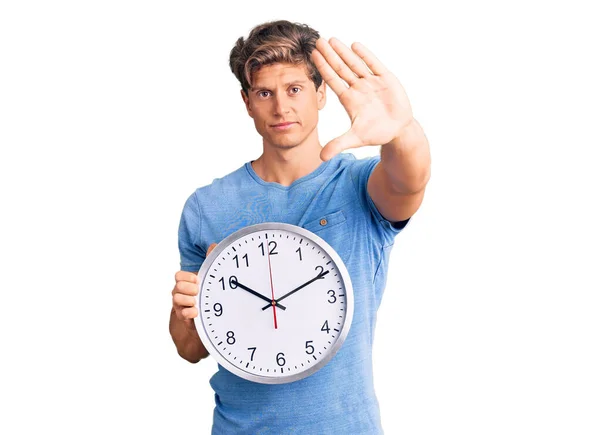 Jovem Homem Bonito Segurando Grande Relógio Com Mão Aberta Fazendo — Fotografia de Stock