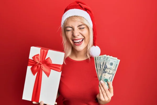 Young Blonde Girl Wearing Christmas Hat Holding Gift Dollars Smiling — Stock Photo, Image