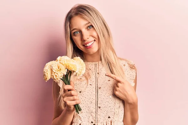 Young Blonde Woman Holding Flowers Smiling Happy Pointing Hand Finger — Stock Photo, Image