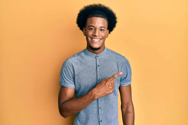 アフリカ系アメリカ人の男とアフロの髪を身に着けているカジュアル服笑顔陽気に指して手と指で側面まで — ストック写真
