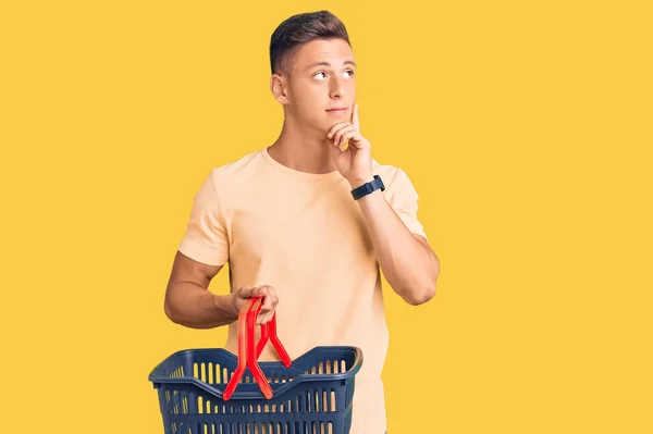 Young Handsome Hispanic Man Holding Supermarket Shopping Basket Serious Face — 스톡 사진