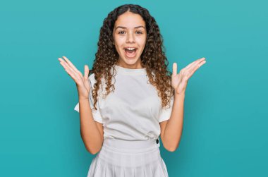 Gündelik beyaz tişört giyen genç İspanyol kız zaferi mutlu bir gülümsemeyle ve kazanan yüz ifadesiyle kutluyor. 