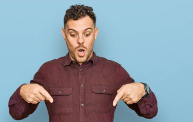Gündelik giysiler giymiş genç İspanyol bir adam parmaklarını göstererek reklamını yapıyor, şaşırmış bir yüz ve ağzını açıyor. 