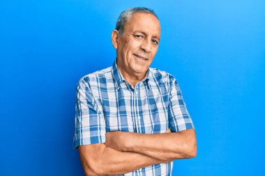 Günlük kıyafetler giyen, kollarını kavuşturup kameraya gülümseyen İspanyol kıdemli bir adam. pozitif kişi. 