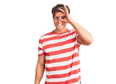 Sıradan kıyafetler giyen genç yakışıklı adam el hareketleriyle gülümsüyor, mutlu yüzüyle parmaklarının arasından bakıyor.. 