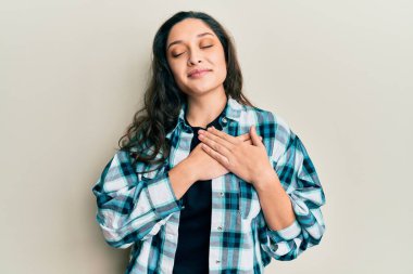 Güzel bir ortadoğulu kadın, sıradan kıyafetler giyiyor, elleri göğsünde gülümsüyor, gözleri kapalı, yüzünde minnet dolu bir jest var. sağlık kavramı. 