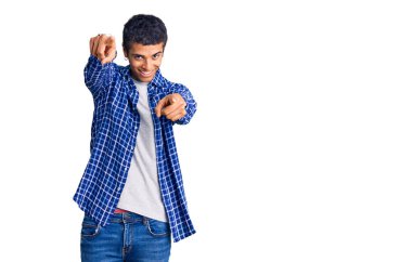 Genç Afro-Amerikan adam günlük giysiler içinde seni ve kamerayı parmaklarıyla göstererek mutlu ve mutlu bir şekilde gülümsüyor. 