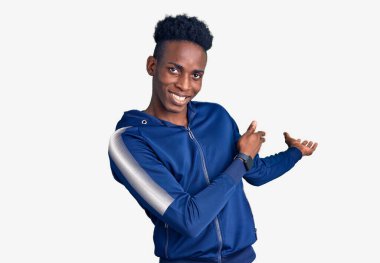 Genç Afro-Amerikan erkek spor giysisi giyiyor ve doğal bir şekilde gülümseyerek içeri girmeye davet ediyor. 