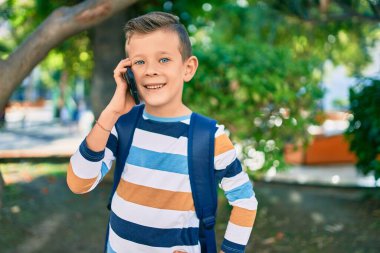 Sevimli beyaz çocuk gülümsüyor. Parktaki akıllı telefondan konuşuyor..