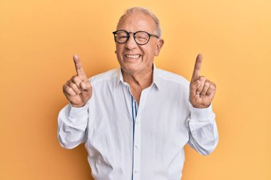 Kıdemli beyaz adam parmaklarını kaldırıp kameraya bakıyor seksi bir ifadeyle, neşeli ve mutlu bir yüzle.. 