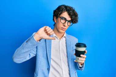Ceket giyen İspanyol asıllı genç adam kızgın yüzlü kahve içerken, olumsuz işaret baş parmakları aşağıda, reddedilme konsepti var. 