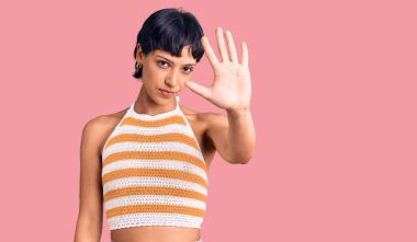 Kısa saçlı, günlük kıyafetler giyen esmer bir kadın avucunun içi gibi şarkı söylemeyi kesiyor. Yüzünde olumsuz ve ciddi bir jest olan uyarı ifadesi. 