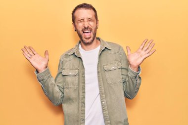 Gündelik kıyafetler giyen genç, çılgın ve çılgın başarıyı kutlayan kollarını kaldırmış, gözlerini kapatmış heyecanlı çığlıklar atan yakışıklı bir adam. Kazanan konsept 