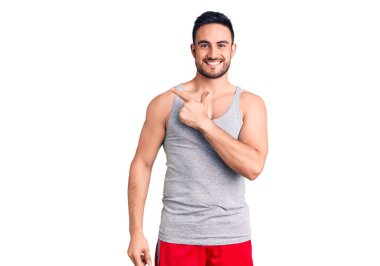 Mayo ve kolsuz tişört giyen genç yakışıklı bir adam. Yüzünde bir gülümseme var. Yüzünde mutlu ve doğal bir ifade var. 