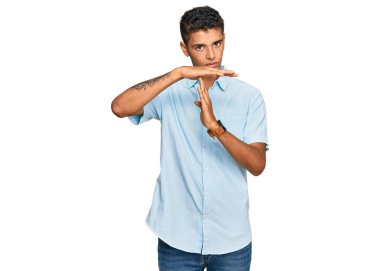 Genç, yakışıklı, Afro-Amerikalı, günlük giysiler giymiş. El kol hareketleri yapıyor. Hayal kırıklığına uğramış ve ciddi bir yüz ifadesi var. 