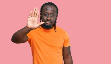 Rahat kıyafetler giyen yakışıklı Afro-Amerikan erkeği avucunun içi gibi şarkı söylemeyi kesiyor. Yüzünde olumsuz ve ciddi bir jest olan uyarı ifadesi. 