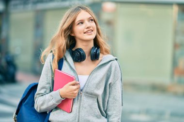 Güzel beyaz öğrenci şehirde kulaklık kullanıyor..