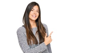 Genç esmer kadın, günlük kışlık süveter giyiyordu. Neşeli, yüzünde mutlu ve doğal bir ifadeyle, elleri ve parmaklarıyla yüzünü gösteren bir gülümseme vardı. 