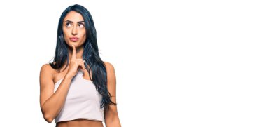 Güzel İspanyol kadın gündelik kıyafetler giyer şüphe üzerine yoğunlaşır çene üstüne parmak ve merak içinde yukarı bakar. 