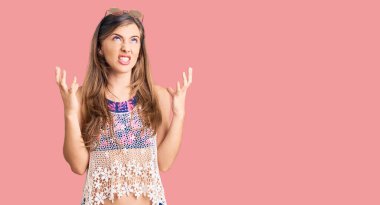 Bikini ve güneş gözlüğü takan güzel, beyaz bir kadın. Deli gibi bağırıyor, agresif bir ifadeyle bağırıyor ve kollarını kaldırıyor. hüsran kavramı. 