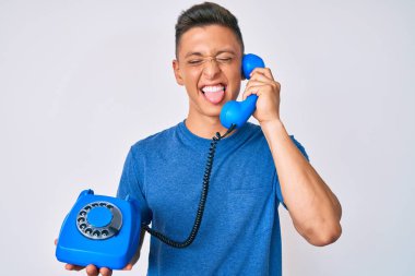 Antika telefon tutan genç İspanyol çocuk komik bir ifadeyle dilini dışarı çıkartıyor.. 