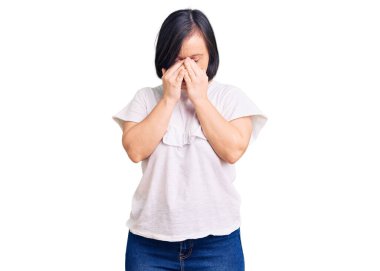 Down sendromlu esmer bir kadın günlük beyaz tişört giyiyor yorgunluk ve baş ağrısı için gözlerini ovuşturuyor, uykulu ve yorgun bir ifade takınıyor. görme sorunu 