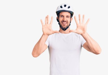 Bisiklet kaskı takan yakışıklı genç adam on numarayı gösterip işaret ederken kendinden emin ve mutlu bir şekilde gülümsüyor.. 