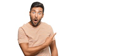 Gündelik giysiler giymiş yakışıklı İspanyol bir adam parmaklarıyla yan tarafı göstererek şaşırdı, ağzı açık hayret içinde kaldı.. 