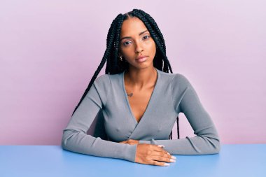 Masada oturan, gündelik kıyafetler giyen güzel İspanyol kadın yüzünde ciddi bir ifadeyle rahatlamış. Basit ve doğal bir şekilde kameraya bakıyorsun.. 