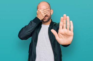 Latin kökenli genç bir adam, günlük kıyafetler giyip, elleriyle gözlerini kapatıyor ve üzgün ve korku ifadeleriyle jestleri durduruyor. utangaç ve olumsuz kavram. 