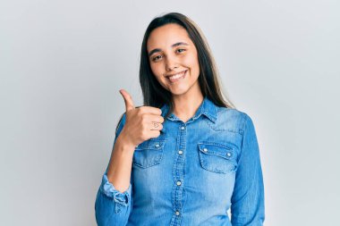 Sıradan kot ceket giyen genç İspanyol kadın elleriyle mutlu bir jest yapıyor. Kameraya bakıp başarıyı gösteren ifade. 