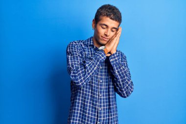 Genç Afro-Amerikan adam günlük kıyafetler giyip uyuyordu. Yorgundu. Hayal kuruyordu ve elleriyle poz veriyordu.. 