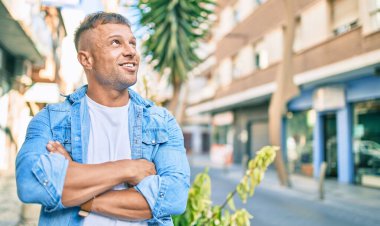 Genç beyaz adam gülümseyerek şehirde mutlu mesut yürüyor..