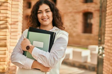 Genç İspanyol öğrenci kadın gülümseyerek şehirde mutlu mesut duruyor..