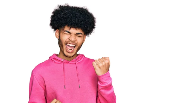 年轻的非洲裔美国男人 身穿宽松的粉色运动衫 高举双臂 闭上眼睛 庆祝成功 获奖者概念 — 图库照片