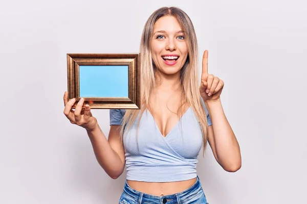 Young Blonde Woman Holding Empty Frame Smiling Idea Question Pointing — Stock Photo, Image