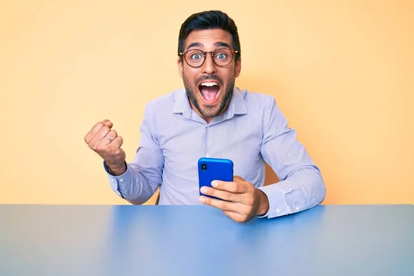 Junger Hispanischer Mann Sitzt Mit Smartphone Auf Dem Tisch Und — Stockfoto