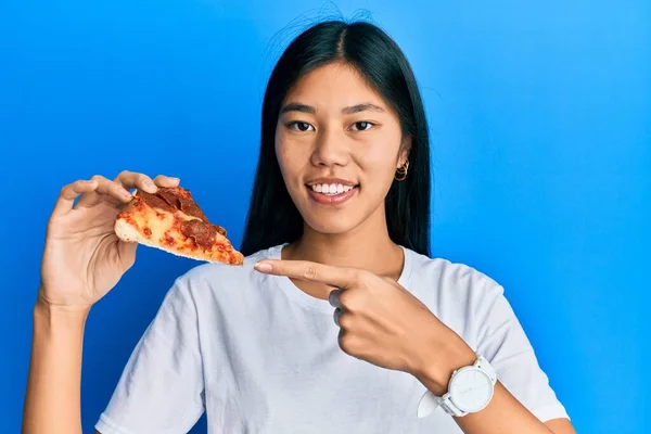 若いです中国の女性食べるおいしいペパロニピザ笑顔幸せなポインティングとともに手と指 — ストック写真