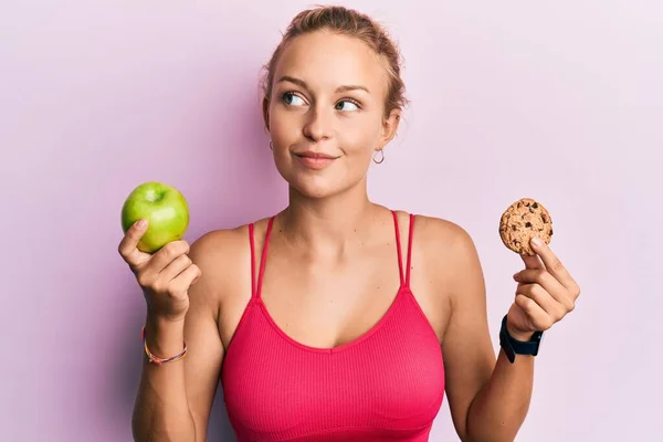 Hermosa Mujer Caucásica Sosteniendo Manzana Verde Galleta Sonriendo Mirando Lado —  Fotos de Stock