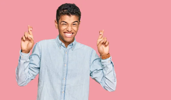 若いハンサムなアフリカ系アメリカ人の男性は カジュアルな服を着て指をジェスチャー希望と目を閉じて笑顔を渡った 幸運と迷信の概念は — ストック写真