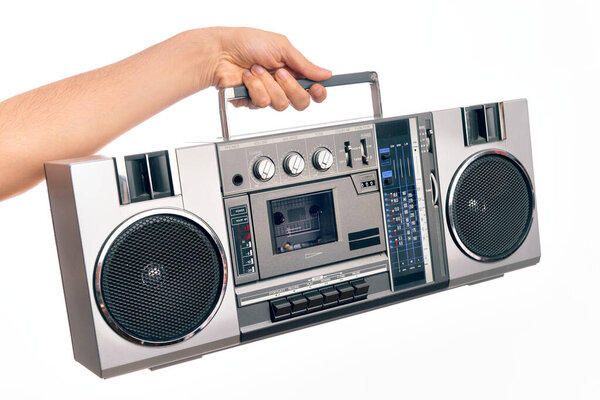 Hand of caucasian young man holding vintage radio cassette over isolated white background