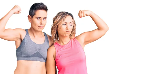 一对夫妇穿着运动服 强壮的男人展示手臂肌肉 自信而自豪的力量 — 图库照片