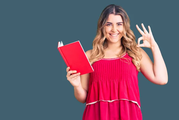 Mulher Caucasiana Jovem Segurando Livro Fazendo Sinal Com Dedos Sorrindo — Fotografia de Stock