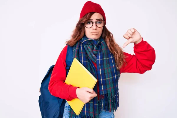 年轻漂亮的女人 戴着冬季围巾 背着学生书包 满脸怒容 消极的标志 不喜欢戴大拇指 拒绝的观念 — 图库照片